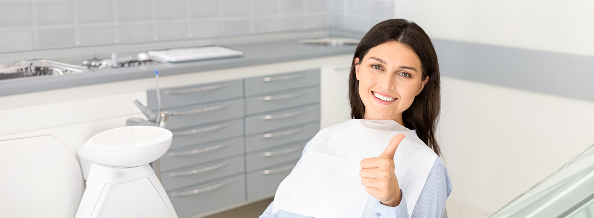 A woman in a kitchen giving a thumbs-up, smiling at the camera.