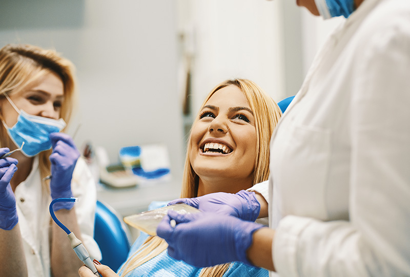 A group of five individuals, possibly dental professionals, in a dental office setting, celebrating with raised hands and thumbs up.