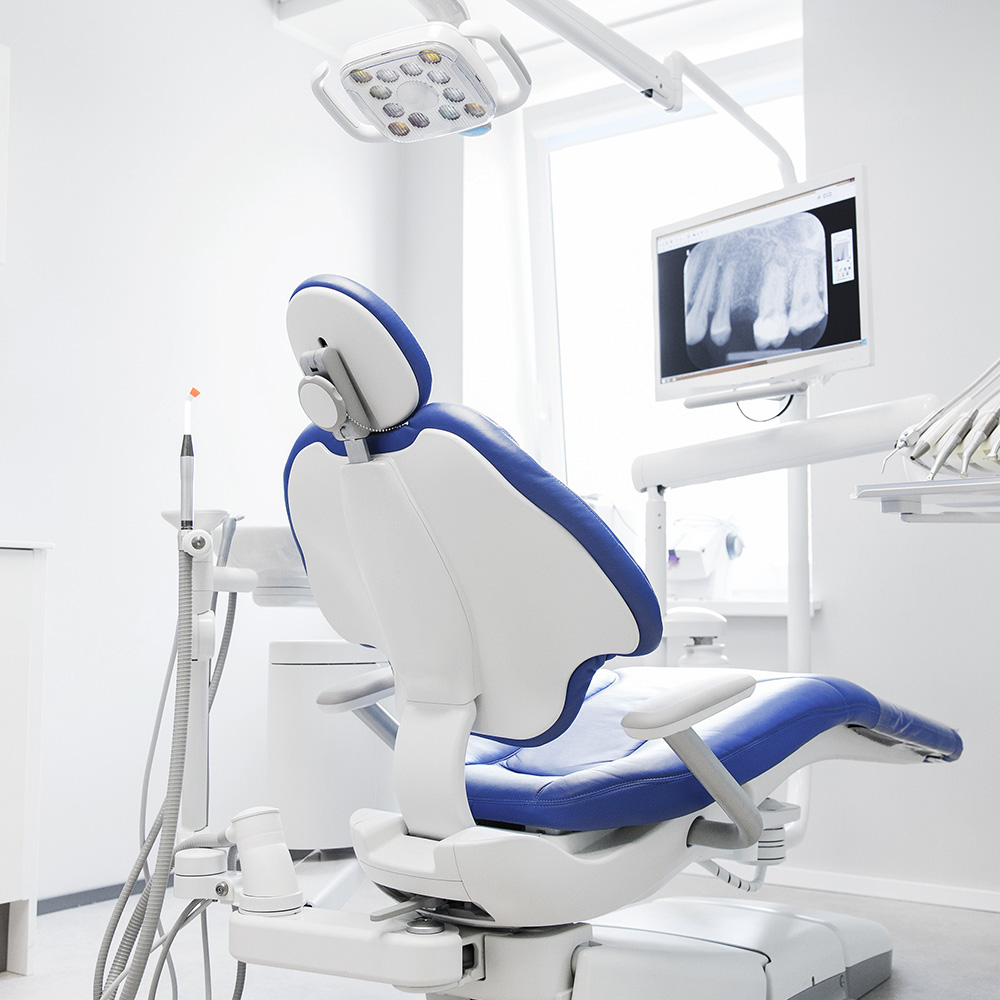 The image shows a dental office interior with a dental chair, a dental light, and various dental equipment.