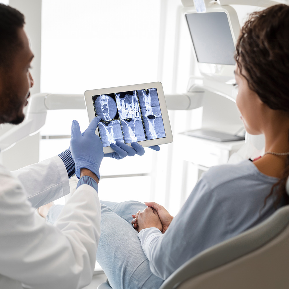A dental professional is assisting a patient with a digital display of the patient s mouth, highlighting dental work in progress.