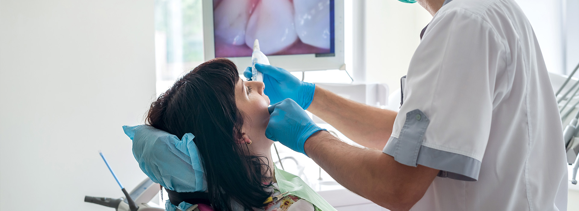 The image shows a dental professional performing a procedure on a patient in a clinical setting.