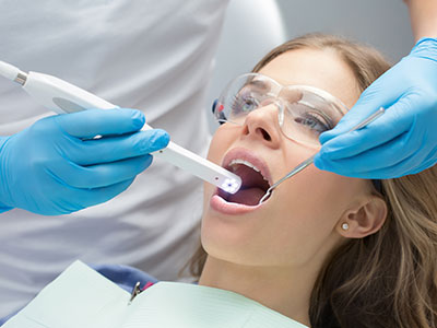 A woman receiving dental treatment, with a dentist using an instrument to examine her mouth.